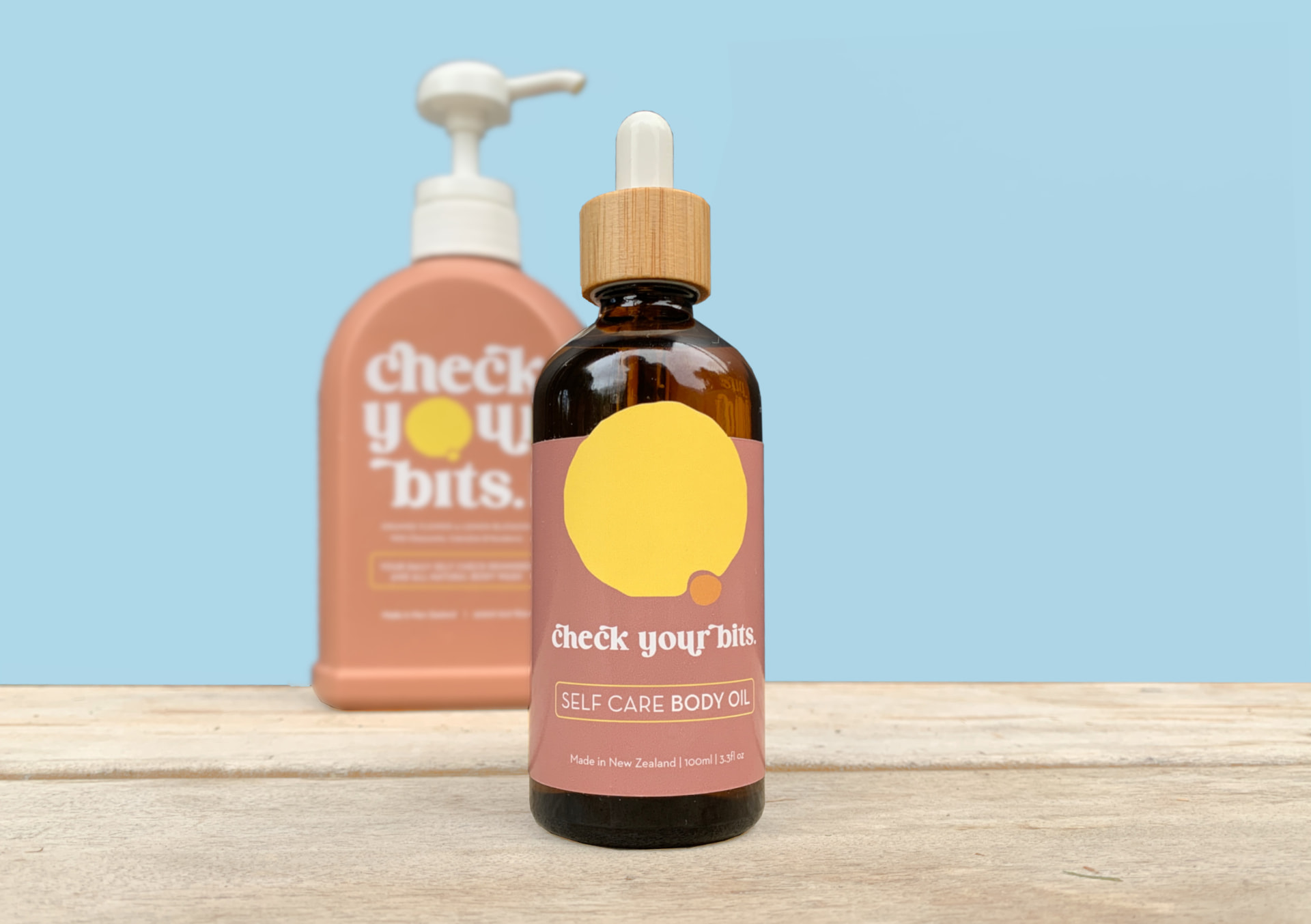Check Your Bits body wash and self care body oil together against a blue backdrop